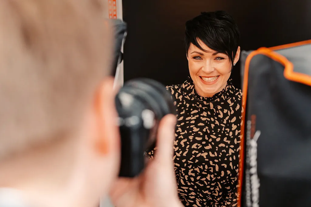 Lachenden Frau beim Fotoshooting in der Zahnarztpraxis, aufgenommen von einem Zahnarzt mit professioneller Ausrüstung.