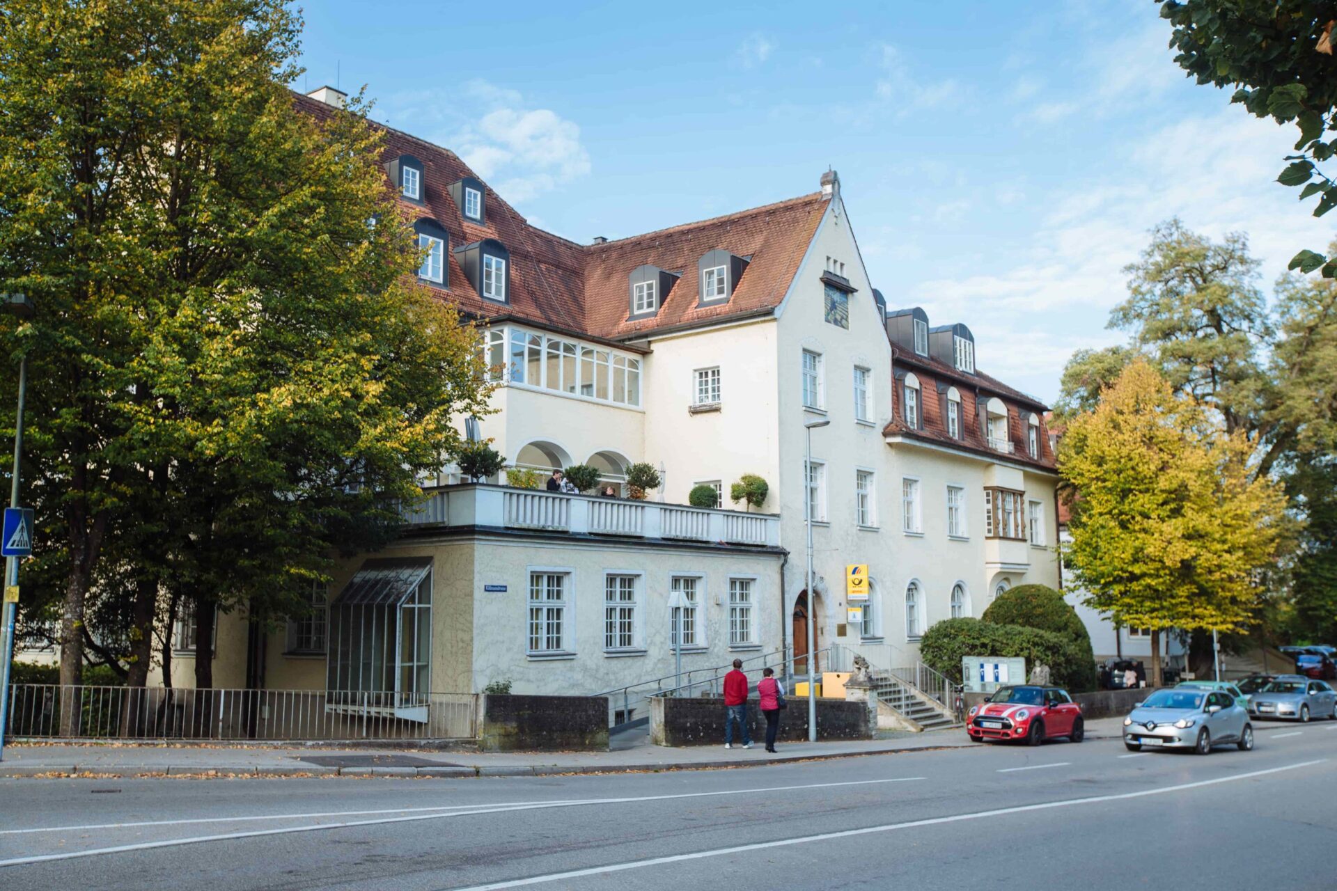 Außenansicht der Zahnarztpraxis Dr. Bayer & Kollegen in der Von-Kühlmann-Straße 1 in Landsberg mit gelber Fassade und rotem Satteldach.