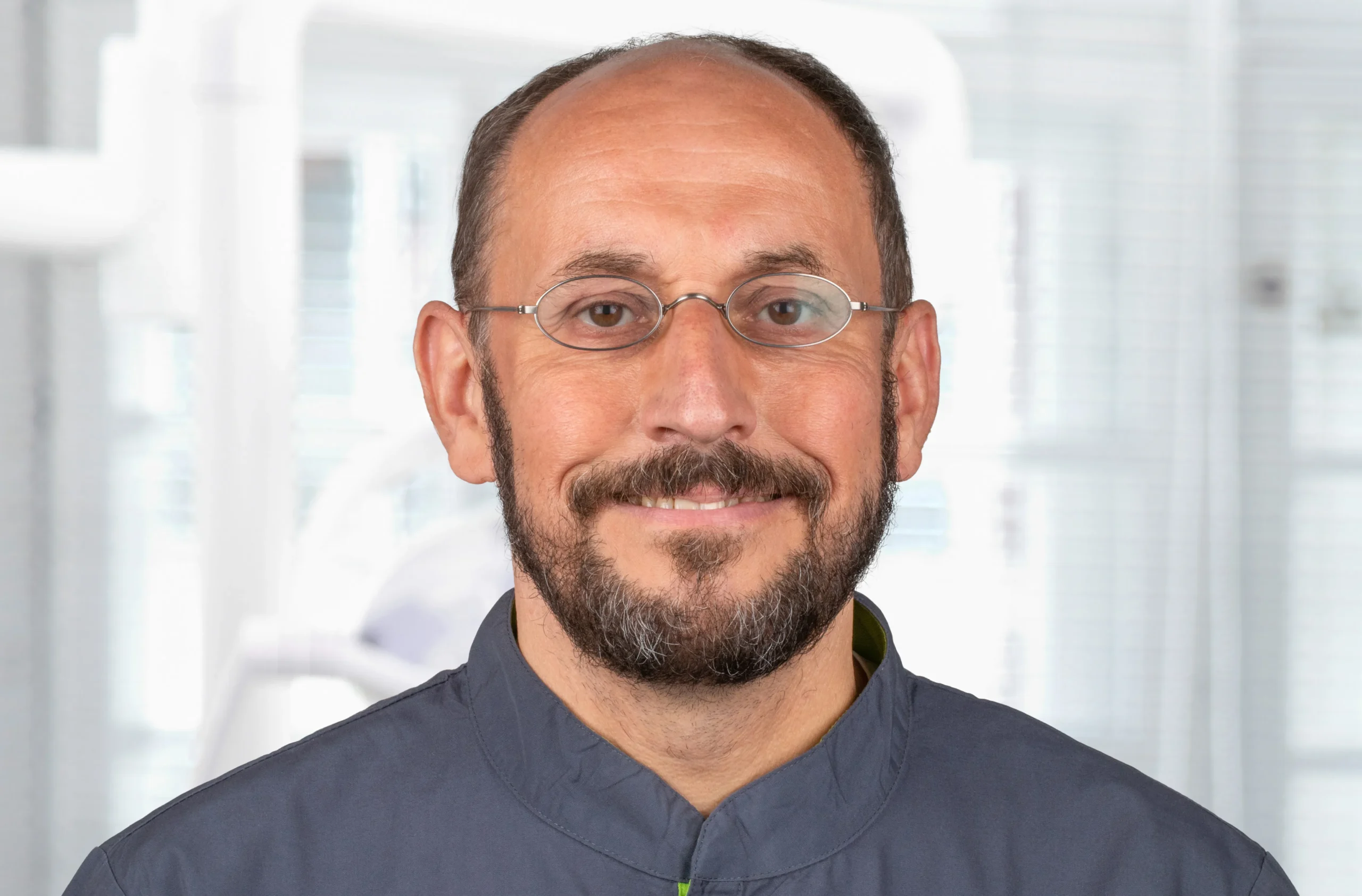 Porträt von Prof. Dr. Jörg Neugebauer mit Brille, dunkelblauem Kasack und freundlichem Blick – Experte für Implantologie bei Dr. Bayer & Kollegen in Landsberg.