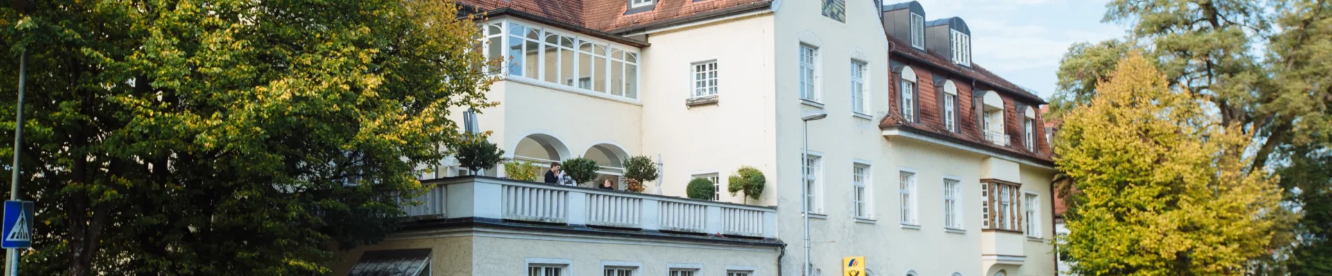 Außenansicht der Zahnarztpraxis Dr. Bayer & Kollegen in der Von-Kühlmann-Straße 1 in Landsberg mit gelber Fassade und rotem Satteldach.