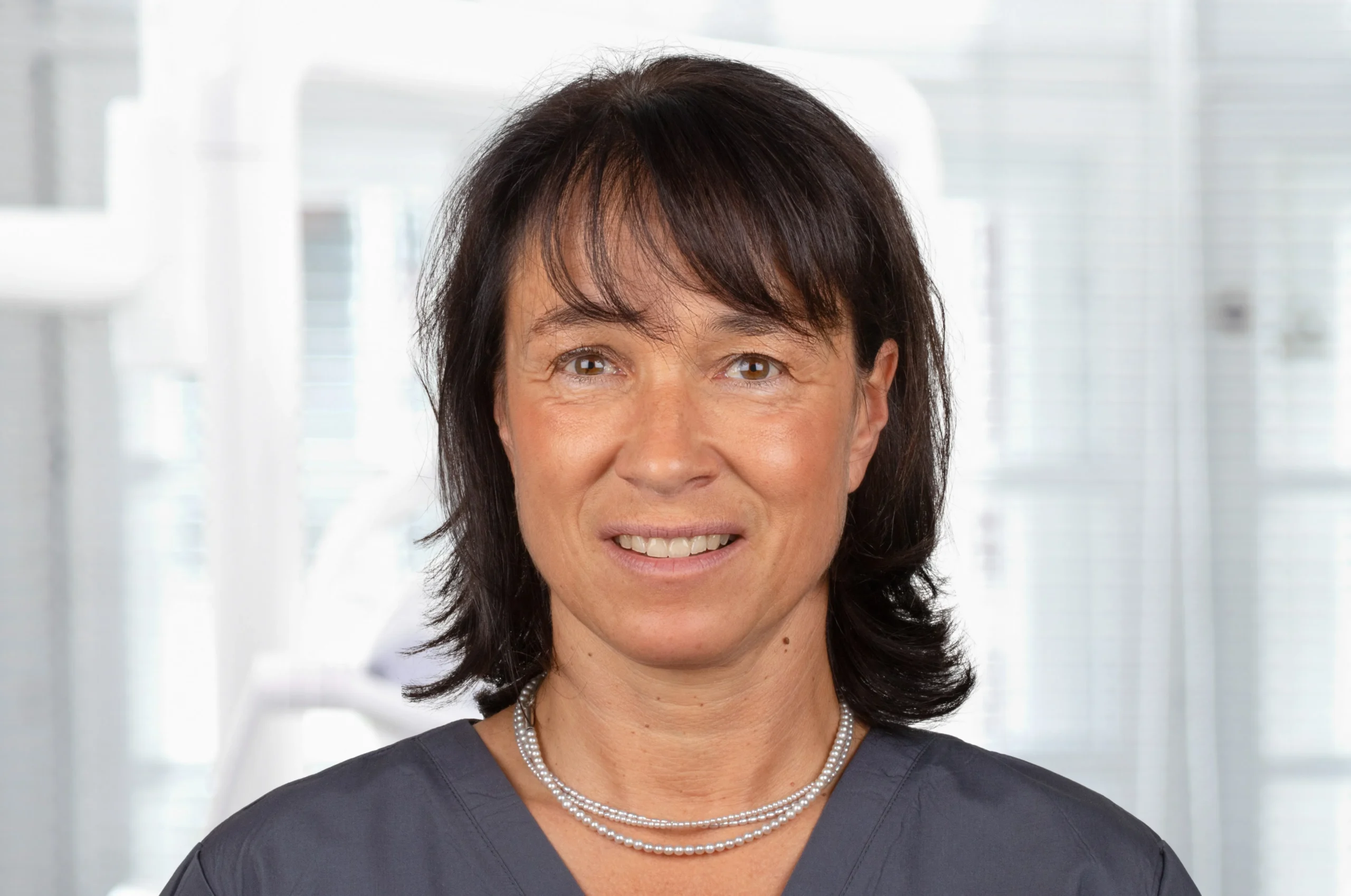Porträt von Dr. Alexandra Elbertzhagen mit dunklem Kasack – Zahnärztin bei Dr. Bayer & Kollegen in Landsberg, spezialisiert auf Zahnerhalt und Behandlung von Angstpatienten.