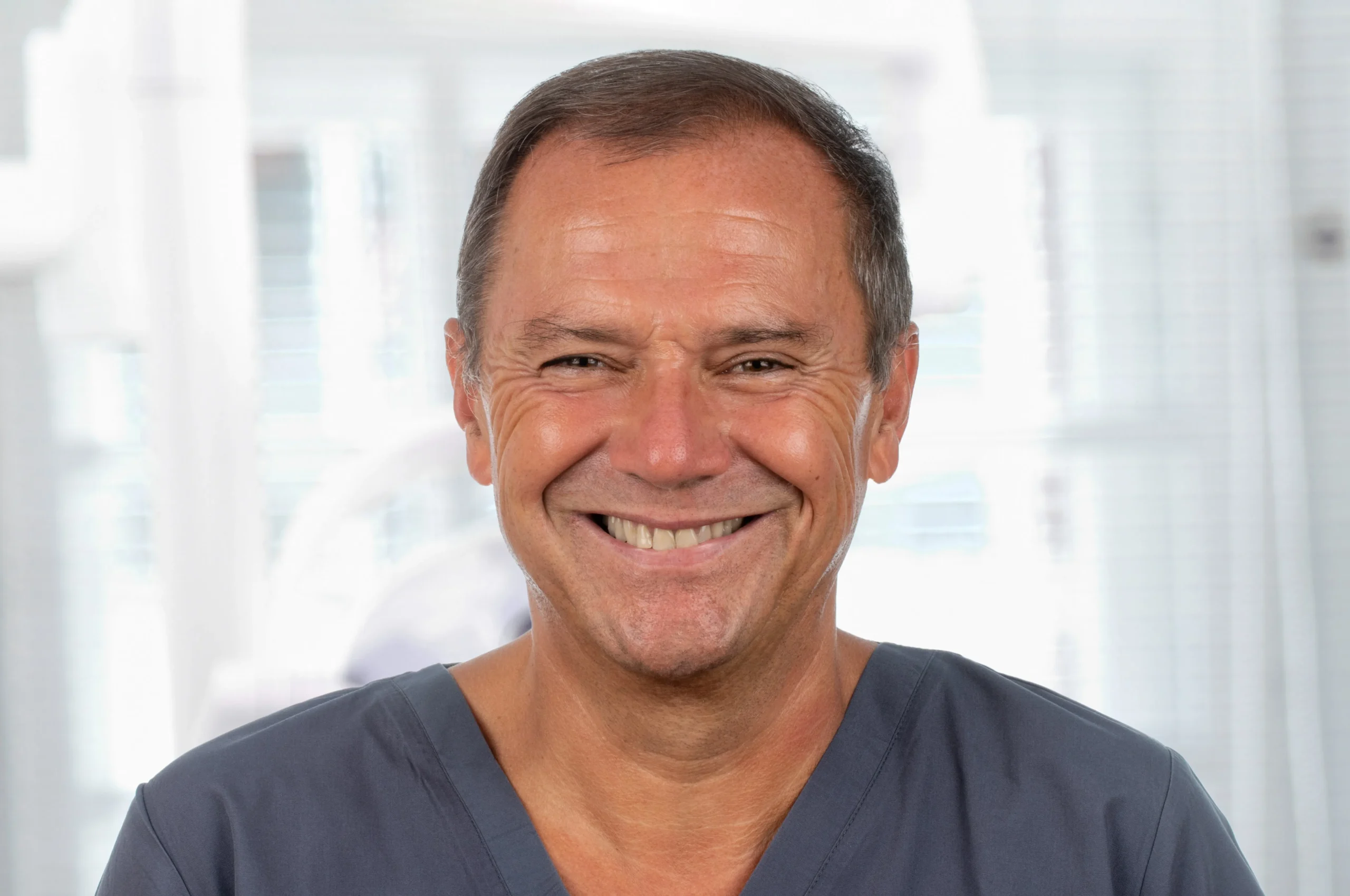 Porträt von Dr. Georg Bayer mit dunklem Kasack und herzlichem Lächeln – Zahnarzt bei Dr. Bayer & Kollegen in Landsberg, spezialisiert auf Implantologie und Oralchirurgie.