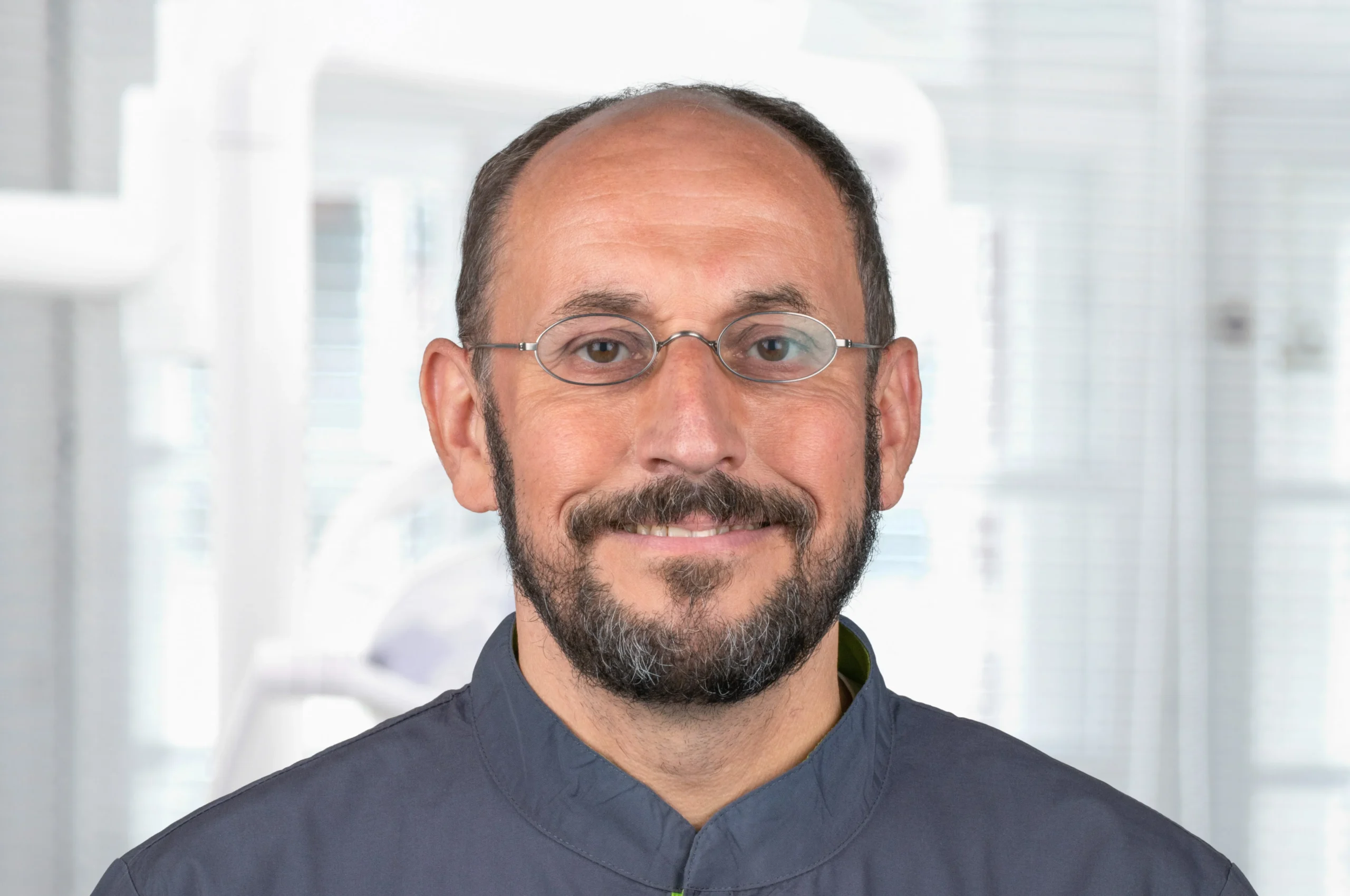 Porträt von Prof. Dr. Jörg Neugebauer mit Brille, dunkelblauem Kasack und freundlichem Blick – Experte für Implantologie bei Dr. Bayer & Kollegen in Landsberg.