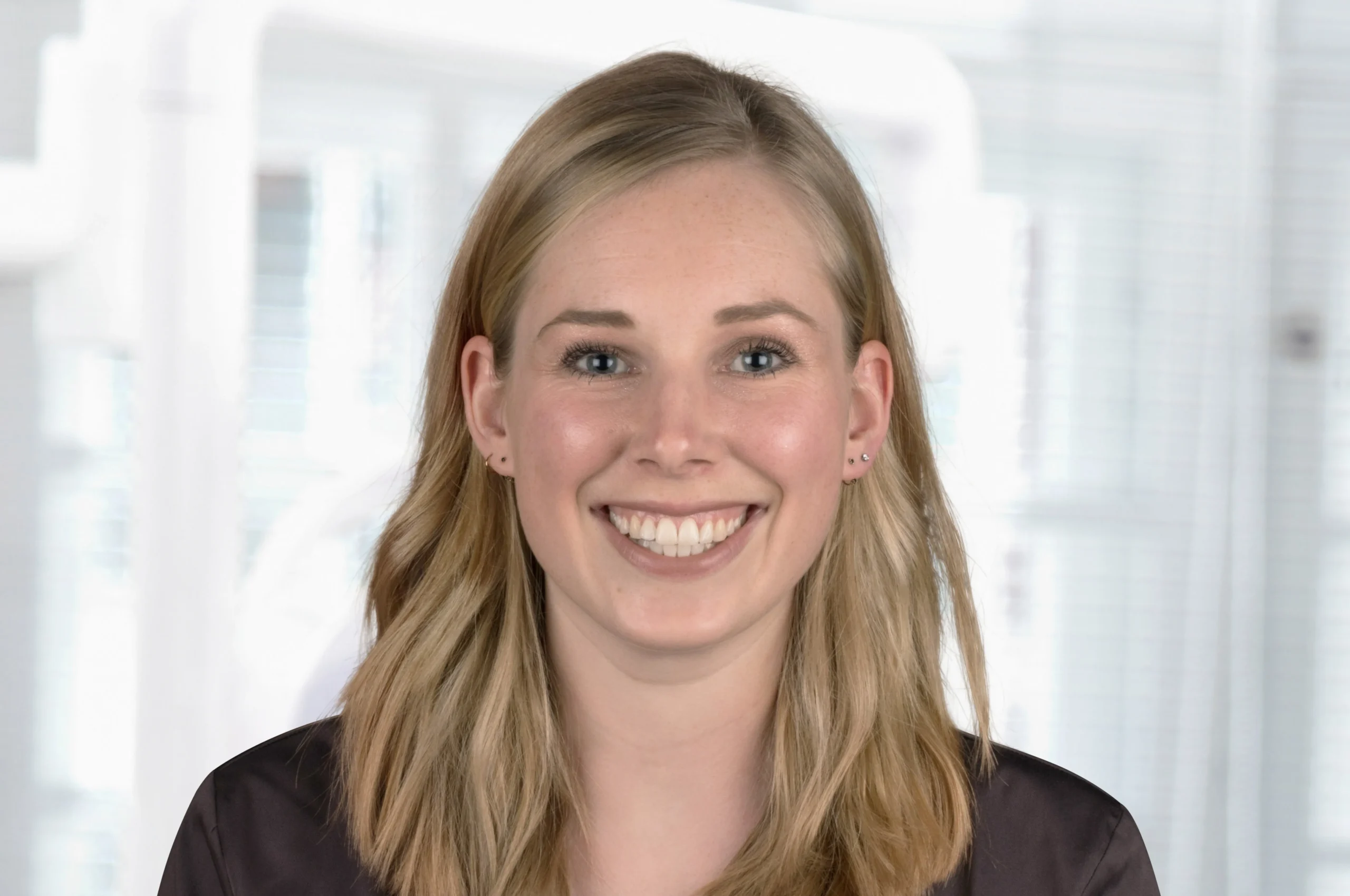 Porträt von Dr. Laura Suchy mit dunkler Praxiskleidung und strahlendem Lächeln – Zahnärztin bei Dr. Bayer & Kollegen in Landsberg.