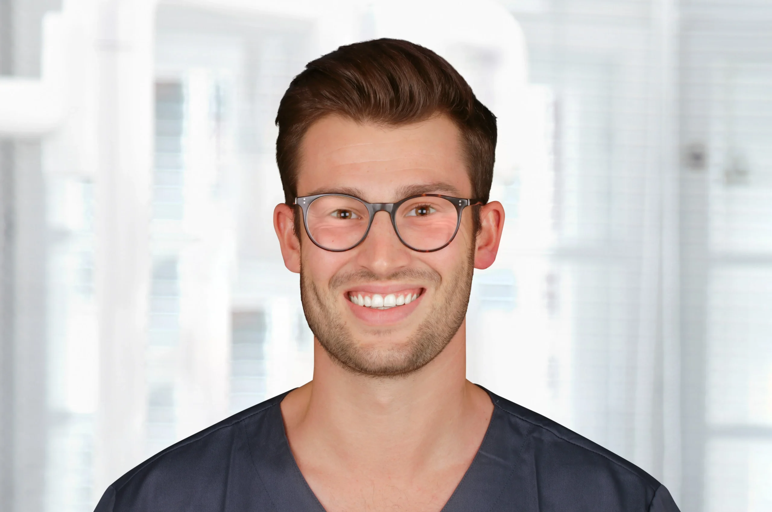 Porträt von Dr. Marius Müller mit Brille und dunkler Praxiskleidung, lächelt freundlich in die Kamera – Mitarbeiter der Praxis Dr. Bayer & Kollegen.