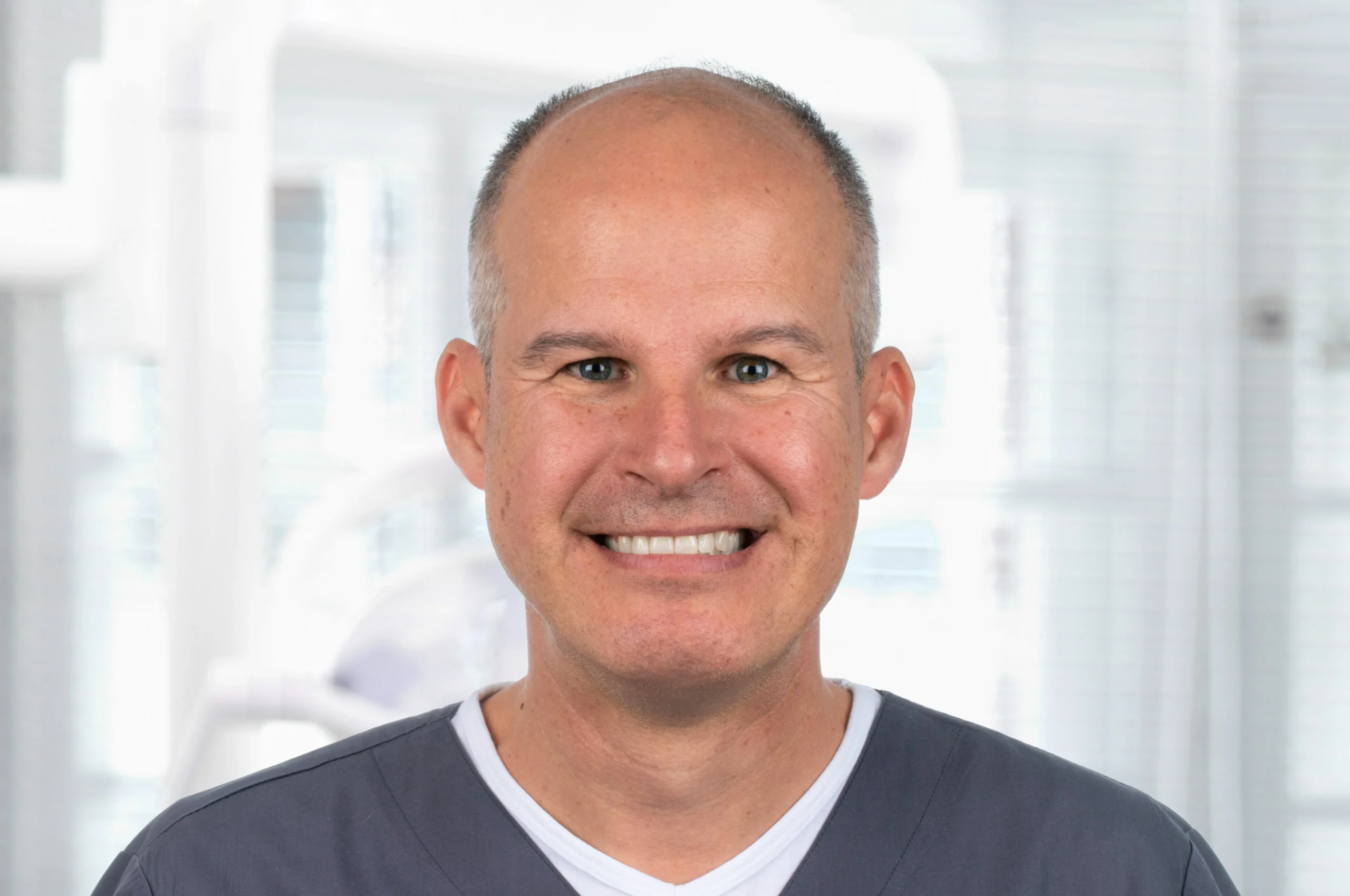 Porträt von Dr. Steffen Kistler mit dunklem Kasack und freundlichem Lächeln – Zahnarzt bei Dr. Bayer & Kollegen in Landsberg, spezialisiert auf Prothetik, Implantologie und ästhetische Zahnheilkunde.
