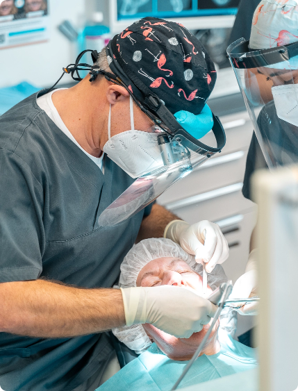 Zahnarzt mit Schutzvisier bei implantologischer Behandlung unter sterilen OP-Bedingungen – moderne oralchirurgische Eingriffe in der Zahnarztpraxis Landsberg.